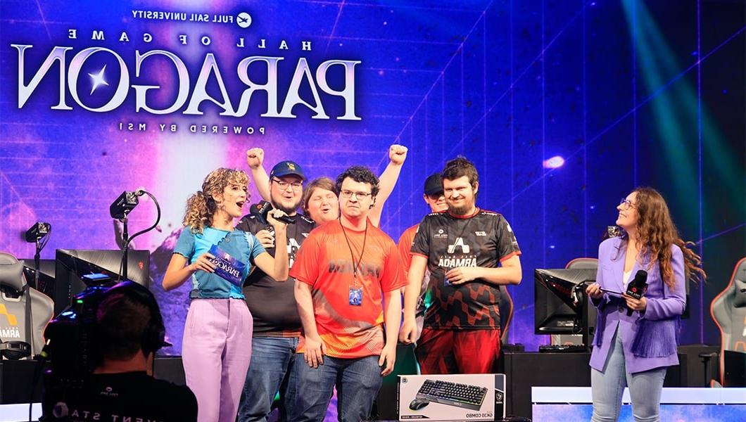 A group of players in various 满帆 无敌舰队 team jerseys on stage in the Fortress with hosts, the screen behind them reads “Hall of Game Paragon Powered by MSI.”